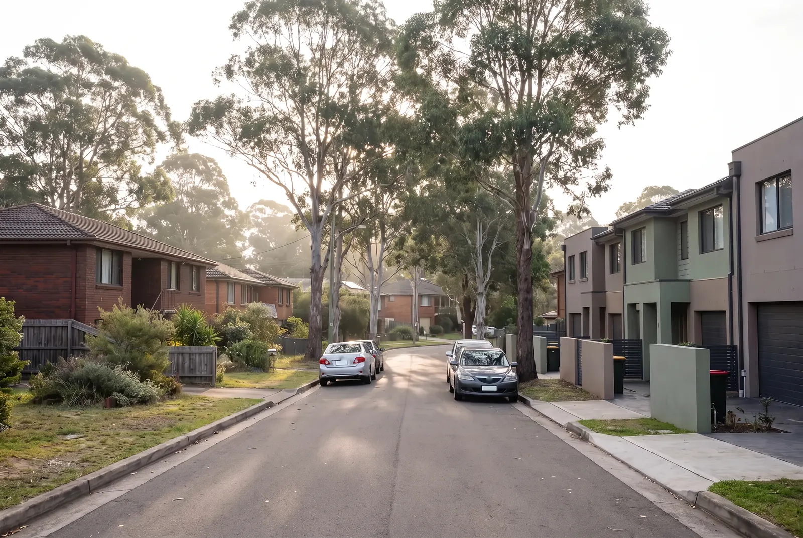 A leafy street with brick houses on one side and a newer row of two-storey townhouses on the other